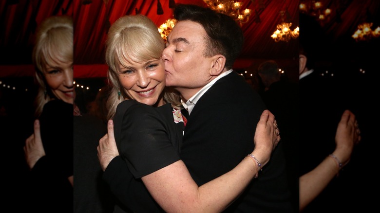 Kelly Tisdale smiling as Mike Myers closes his eyes and kisses her