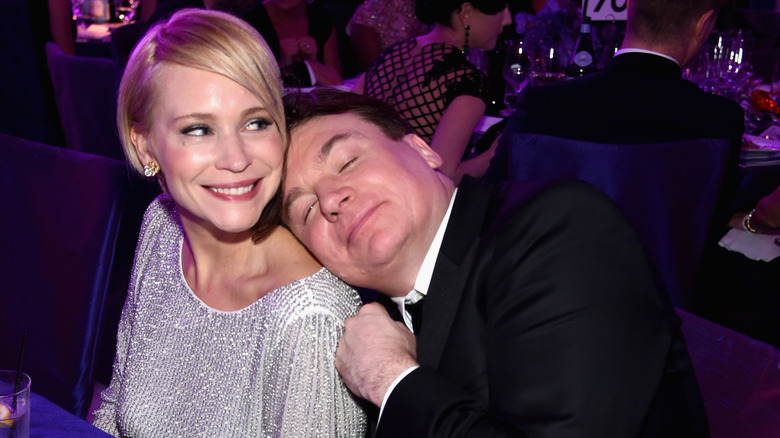 Kelly Tisdale smiling as Mike Myers closes his eyes and rests his head on her shoulder