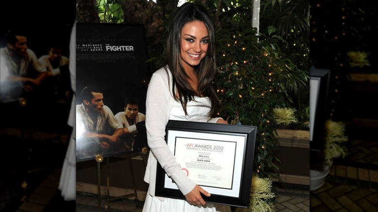 Mila Kunis holding the "Year of Excellance" Award at the AFI Awards (2011)