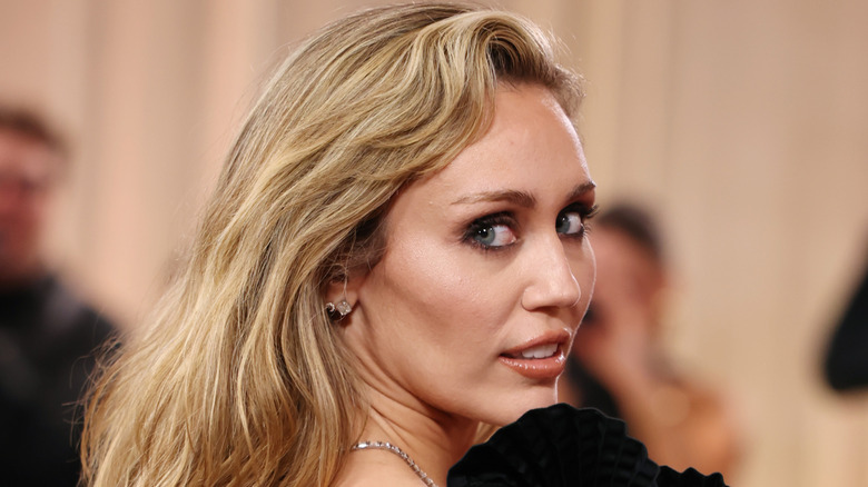 image of Miley Cyrus looking backwards on the red carpet of an event