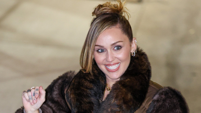 Miley Cyrus wearing a furry coat and smiling