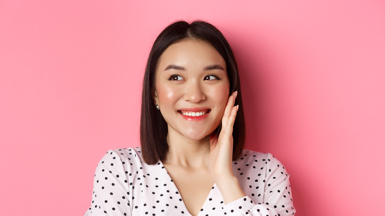 woman touching face pink background