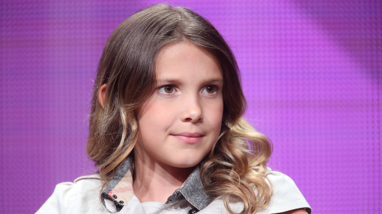 Millie Bobby Brown speaking on stage in 2014 with purple background