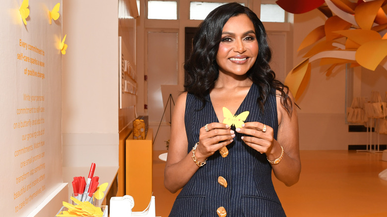 Mindy Kaling smiling with a butterfly-shaped paper