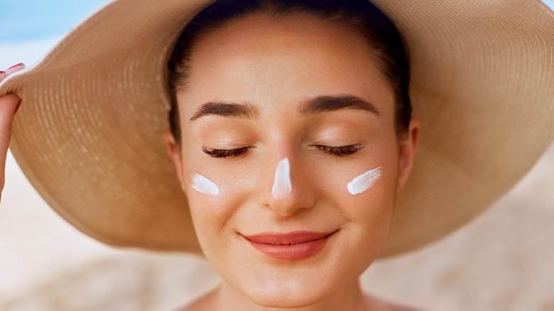 Woman wearing sun hat and sunscreen on face