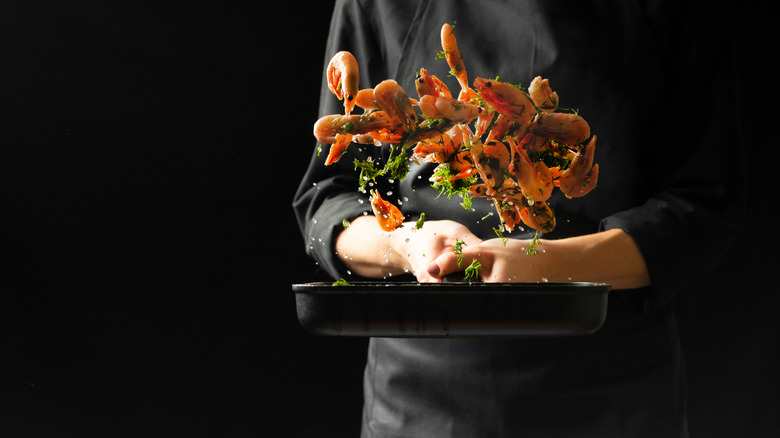 chef sautéing shrimp with greens 
