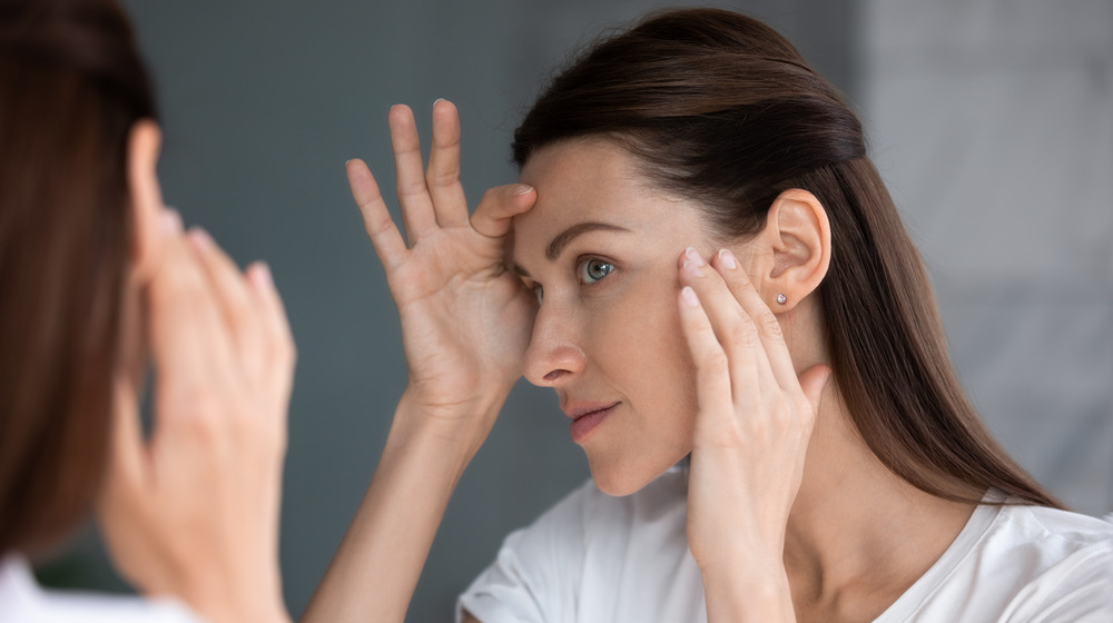 Woman inspecting skin in mirror