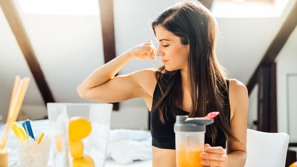 Woman with beverage flexing muscles 