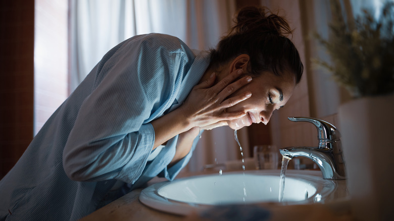 Woman washing her face at night