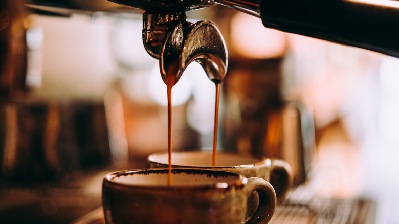 Espresso dripping from a portafilter into cups