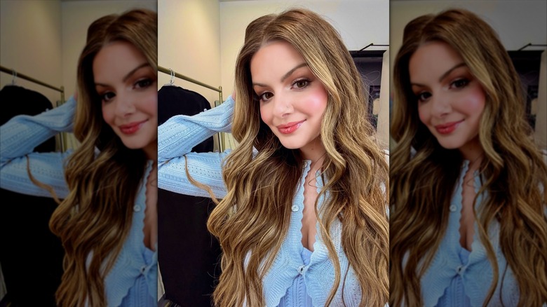 Ariel Winter taking a selfie in a light blue sweater with long brown hair with golden blonde highlights