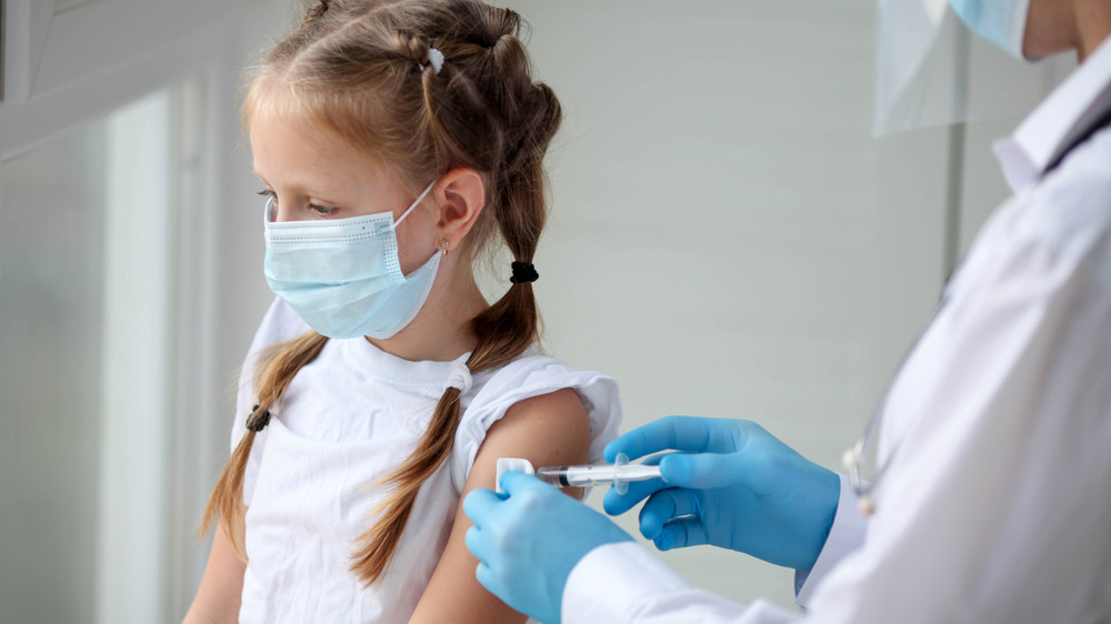 Little girl with face mask getting shot