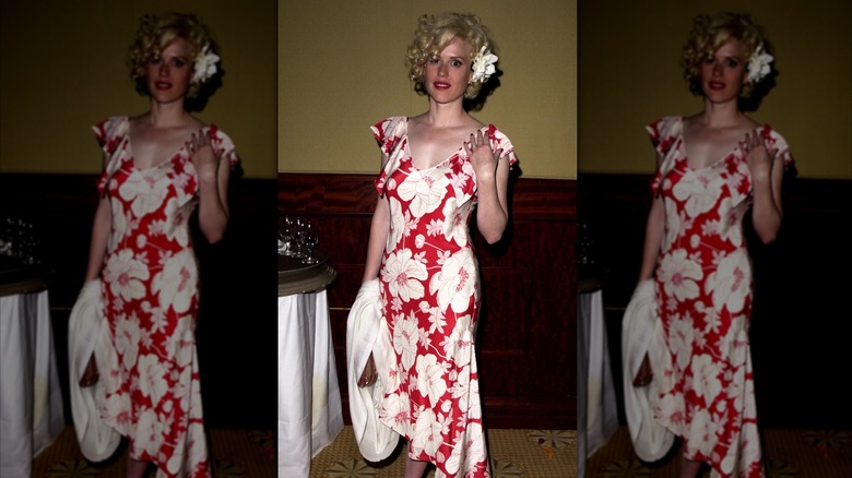 Molly Ringwald poses in a red-and-white flower-print dress