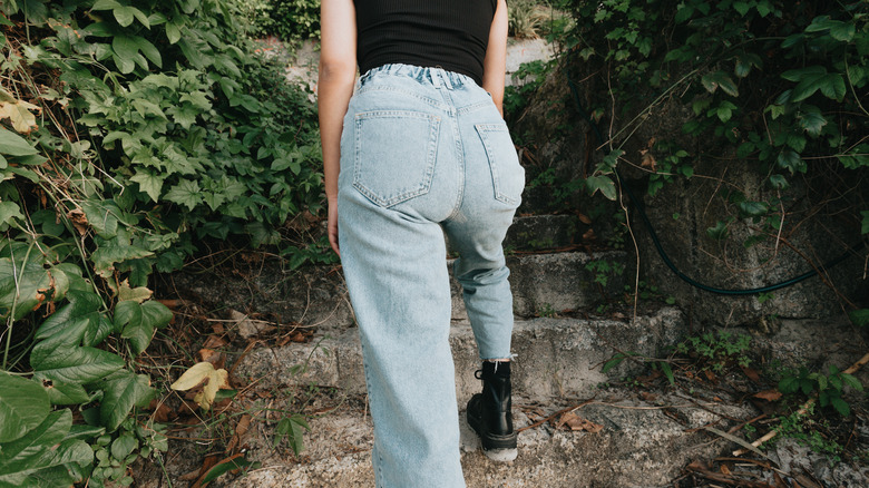 woman stands in high-waisted jeans