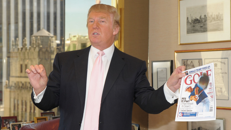 Donald Trump holds up a copy of Golf magazine.