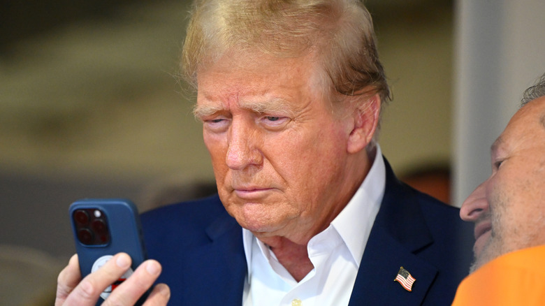 Donald Trump frowns while looking at his phone.