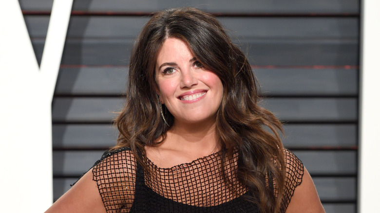 Monica Lewinsky on a red carpet, hands on hips in a black dress.