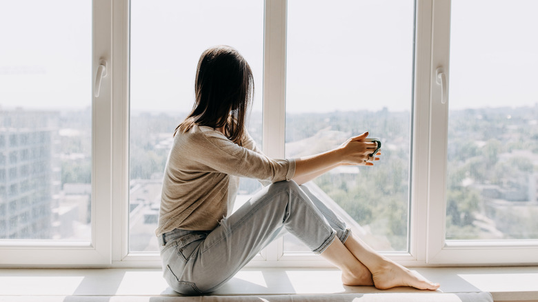 Woman holding a mug looking out a window