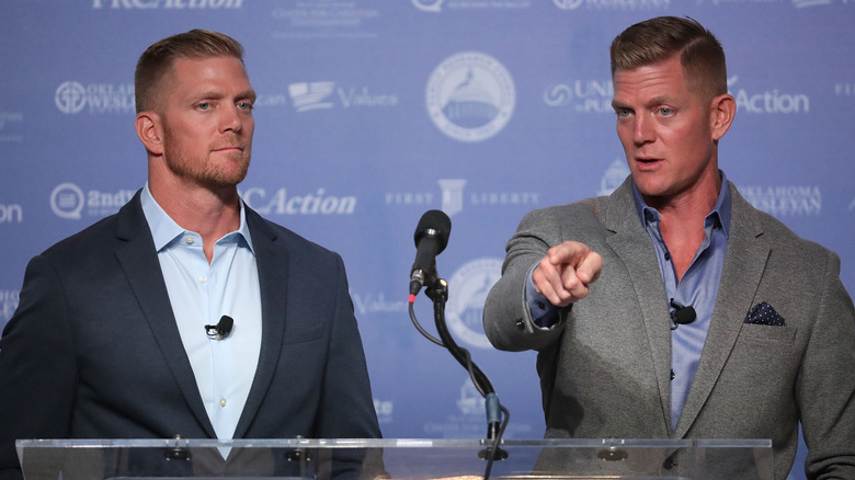 David Benham and Jason Benham standing at a podium and microphone in suits