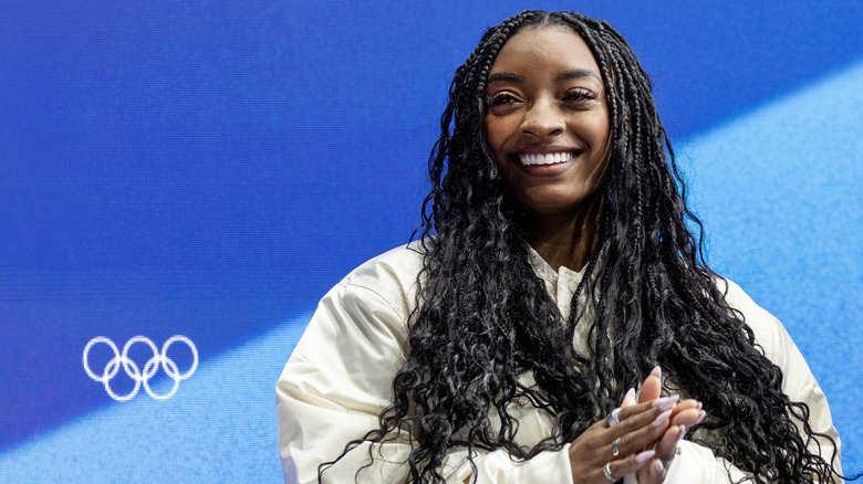 Simone Biles smiling while posing at an Olympics event