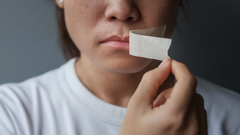 Woman removing tape from mouth