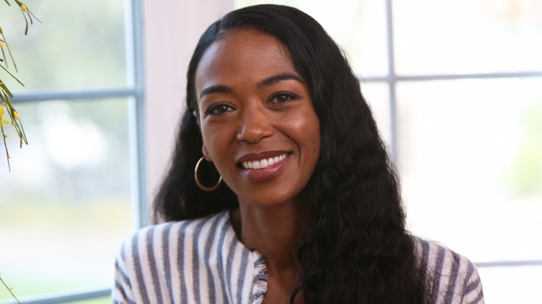 Ananda Lewis sitting in front of a window smiling.