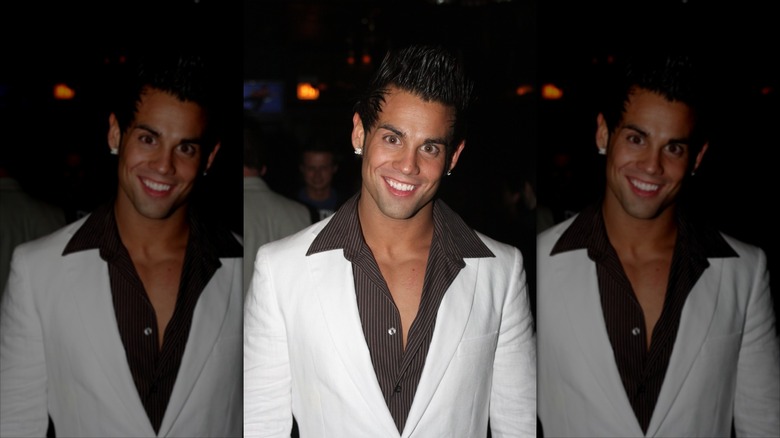 Joey Kovar smiling in a white suit with sharp collars.