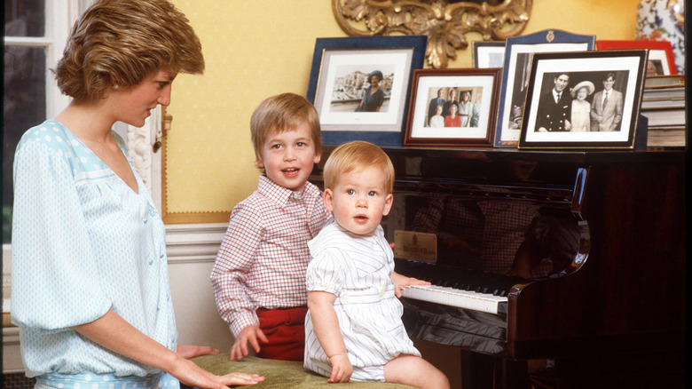 Princess Diana sitting at a piano with young Prince William and Prince Harry