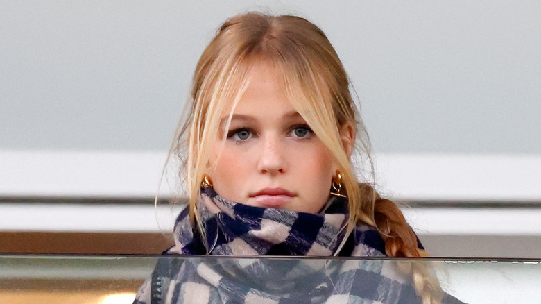 Isla Phillips stares at the camera as she watches sports from a balcony