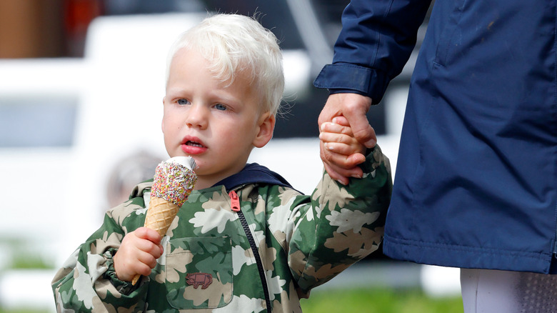 Lucas Tindall holds an ice cream with one hand and Zara Tindall's hand in the other