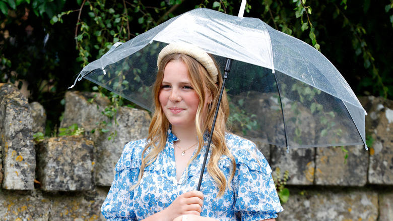 Mia Tindall smiles at onlookers as she carries an umbrella in the rain