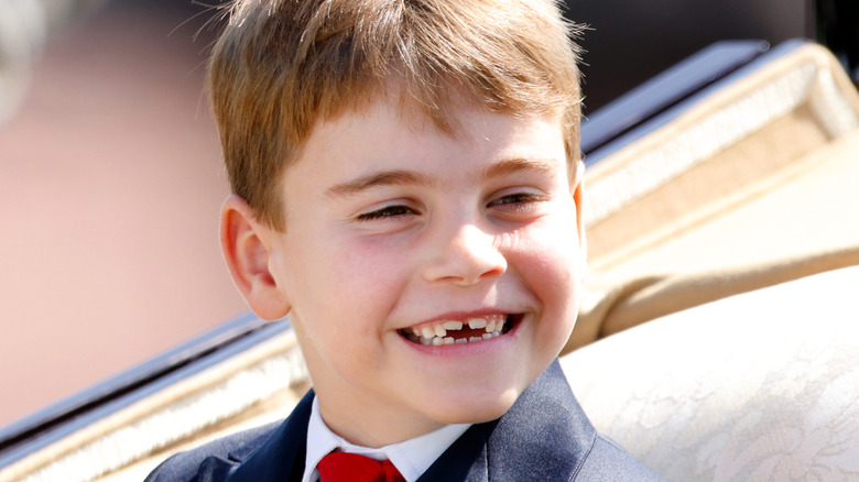 Prince Louis smiles at crowds from an open-top carriage