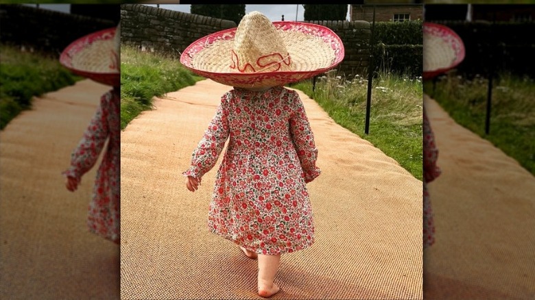 A photo of Sienna Elizabeth Mapelli Mozzi walking away wearing a straw hat