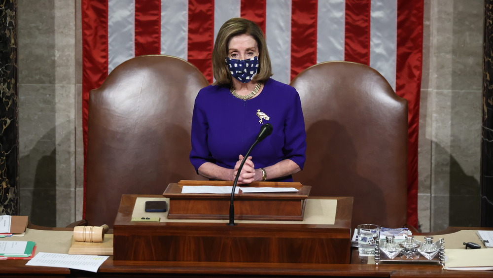 Nancy Pelosi at lectern, wearing blue mask