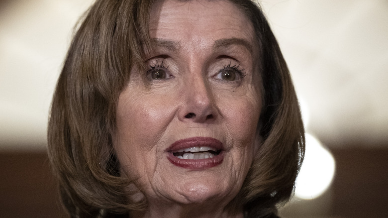 Speaker Pelosi talks to press at podium in blue suit