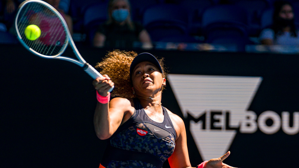 Naomi Osaka playing tennis at a match