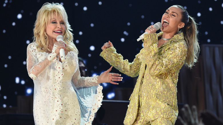 Dolly Parton and Miley Cyrus singing with microphones