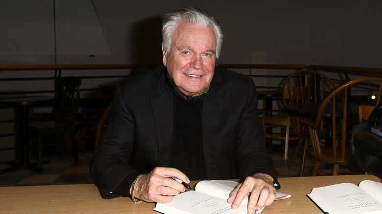Robert Wagner sitting at a desk, signing a book in 2016