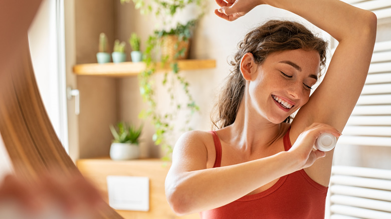 Woman applying deodorant bar to skin