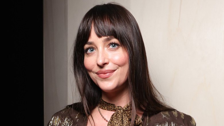 Dakota Johnson in a brown leather jacket and scarf