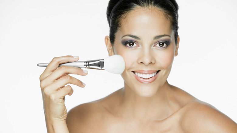 Smiling woman holding a makeup brush