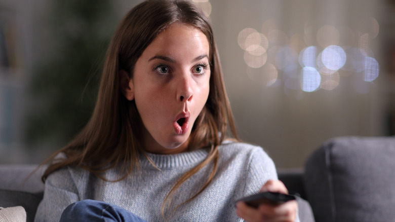 Surprised woman holding TV remote