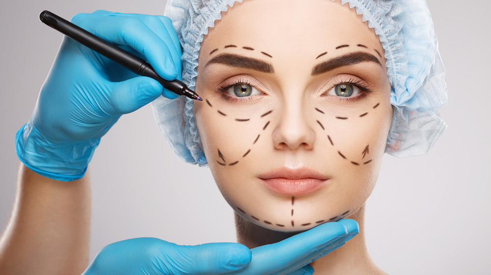 Plastic surgeon draws circles on woman's face