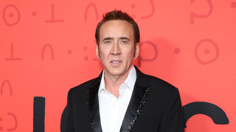 Nicolas Cage in black formals against orange background