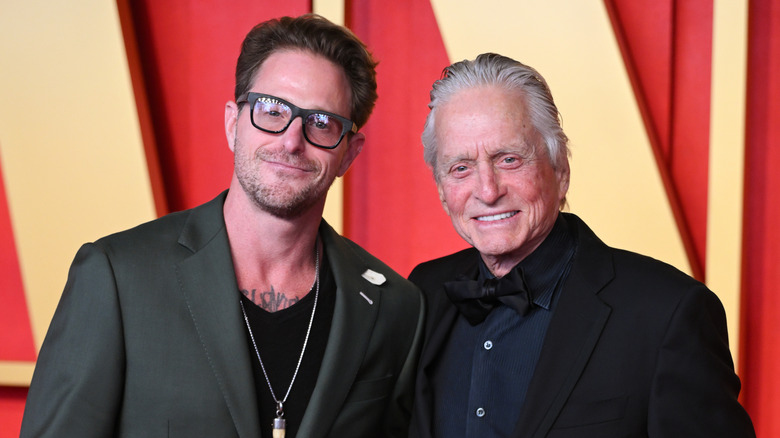 Cameron Douglas in gray blazer wearing glasses with dad Michael Douglas