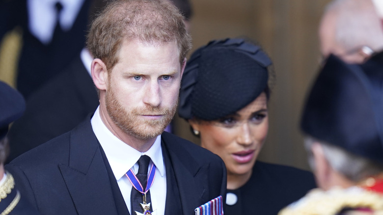 prince harry and meghan markle looking sad in black clothing