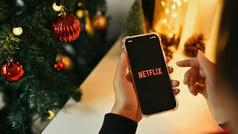 A Christmas tree next to a cellphone displaying the Netflix logo