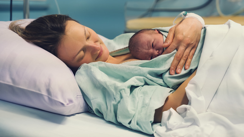 Woman in hospital bed holds newborn baby