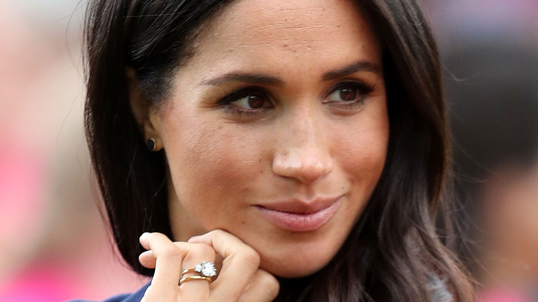 Meghan Markle touches her chin against her hand thoughtfully
