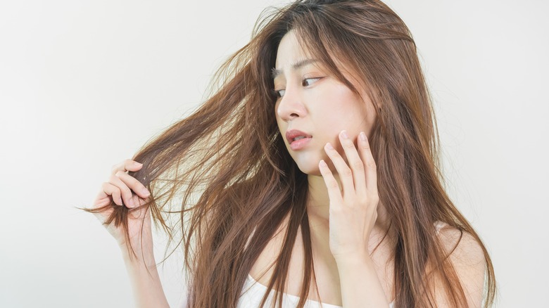 Concerned young woman looking at her hair